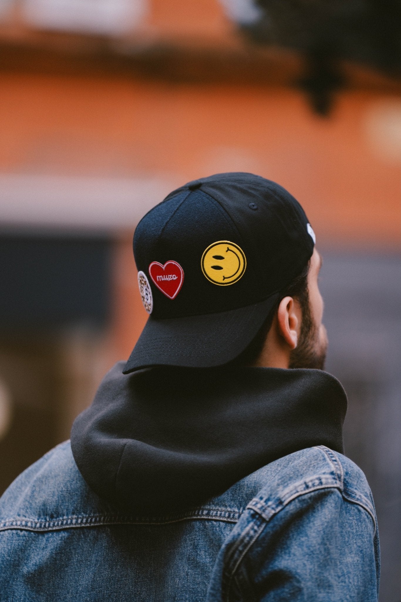 Gros plan arrière d'une casquette Muzo noire personnalisée avec des patchs velcro : un cœur rouge, un hot-dog 'Hot Dog Club' et un piment 'Bomba Latina'. Détail de style streetwear.